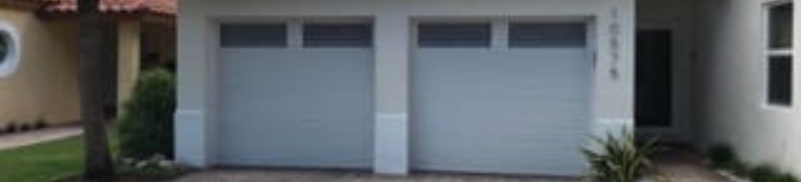 Close-up of newly installed double garage doors with decorative windows in San Marcos, TX.