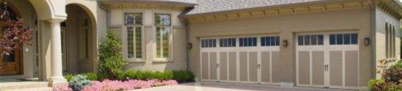 Almond colored Amarr Hillcrest long panel garage doors installed on a new garage in Leander, surrounded by landscaped yard and stone driveway.