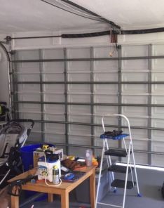 Close-up of a garage door in Cedar Park with rollers out of the track before repair