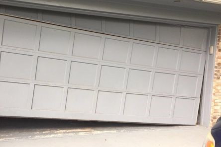 Exterior view of a garage door visibly off track and tilted, requiring professional repair in Cedar Park
