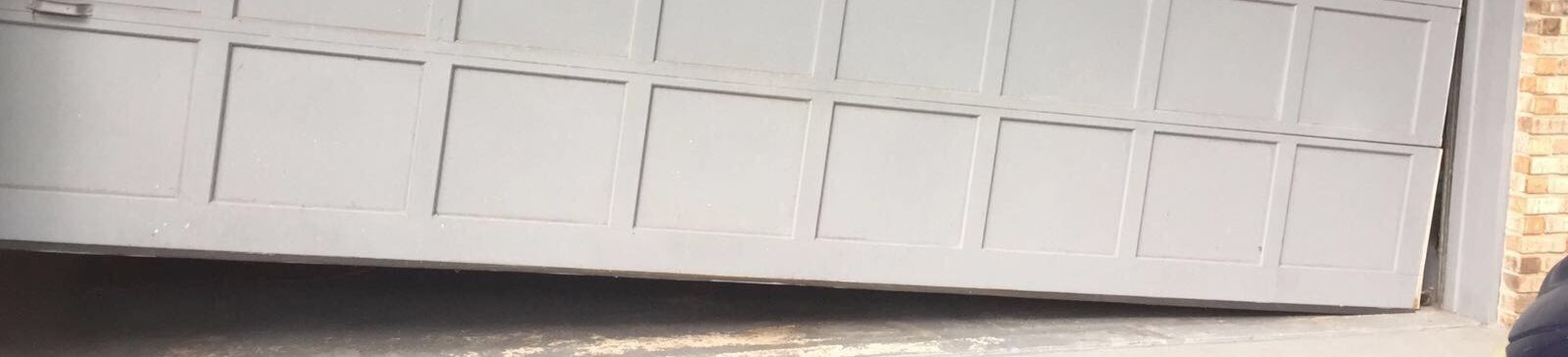 Exterior view of a garage door visibly off track and tilted, requiring professional repair in Cedar Park