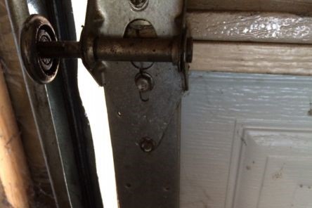 Close-up of misaligned garage door roller off the track before repair in Leander, TX
