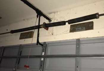 Close-up of a broken garage door extension spring above a gray sectional door in a Jonestown home garage.